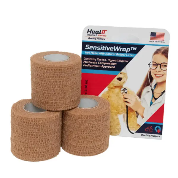 Three rolls of tan compression wrap are stacked in front of SensitiveWrap packaging, which features a child in a lab coat and stethoscope holding a teddy bear.