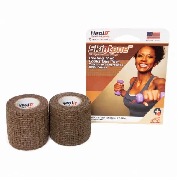 Two rolls of brown compression wrap bandage in front of product packaging featuring a smiling woman holding purple dumbbells, labeled Skintone by HealRT.